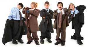 Adorable 7 year old children, boys and girls, in brown and blue baggy men's suits and big shoes over white background.